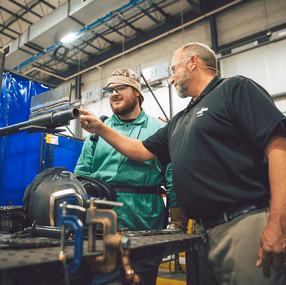 Two men standing and working together on something in a production facility