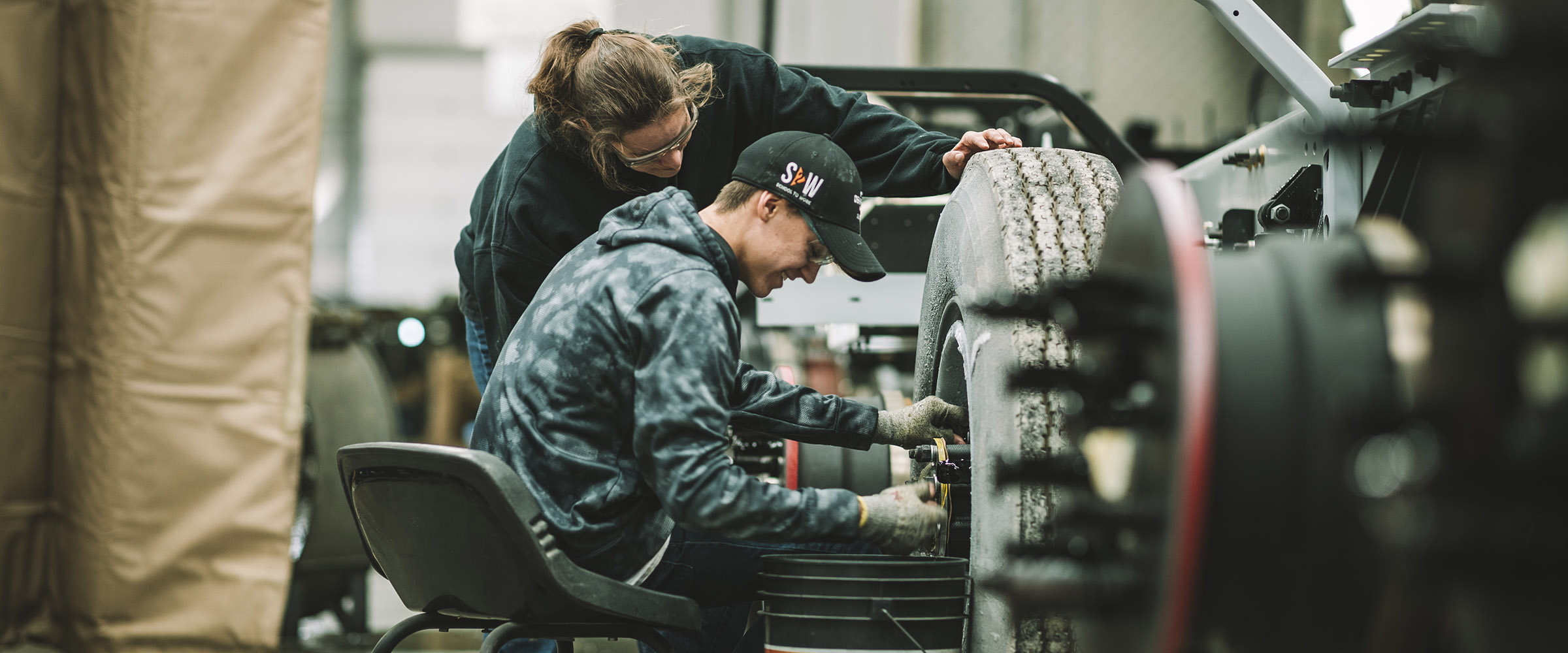 High school student and production worker working on a truck tire