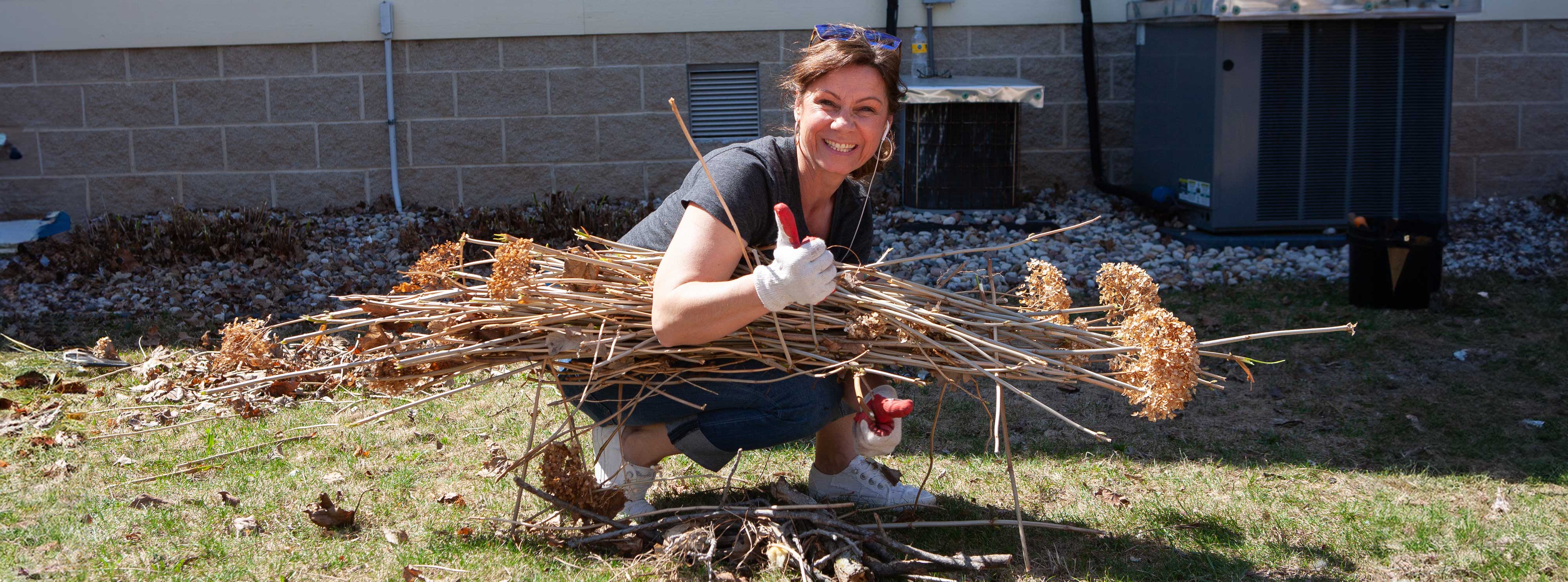 female volunteering outside by picking up sticks