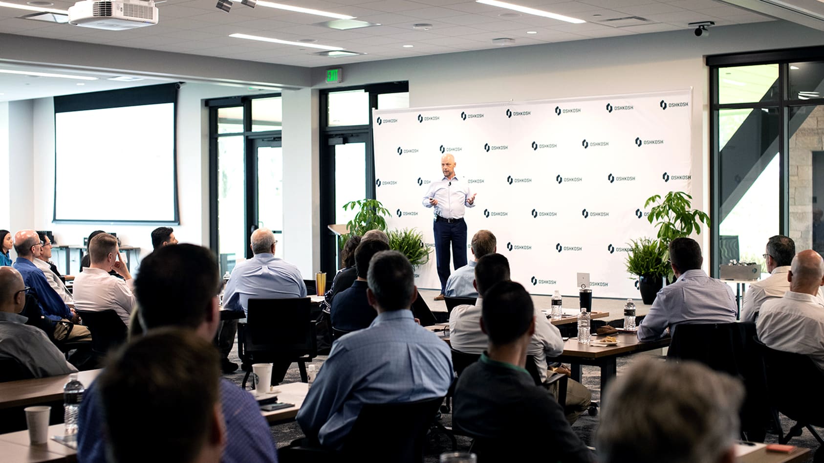 John Pfeifer speaking to other Oshkosh executives in a large conference room at the global headquarters