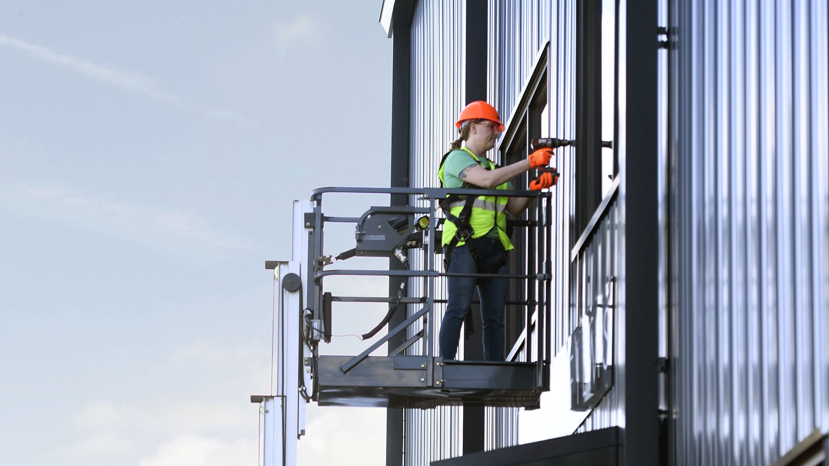 Female on a JLG lift wearing personal protectant equipment fixing the exterior of a building