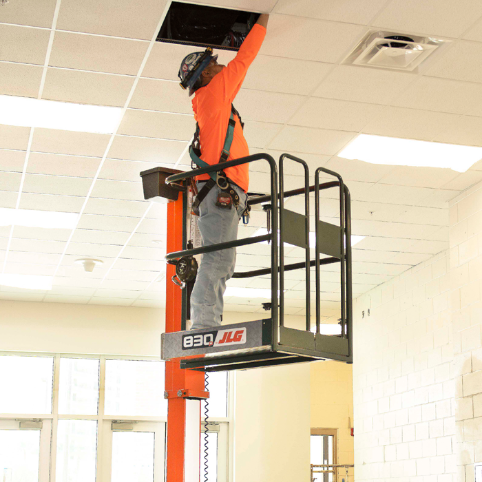 Operator completing facility maintenance with JLG® 830P lift