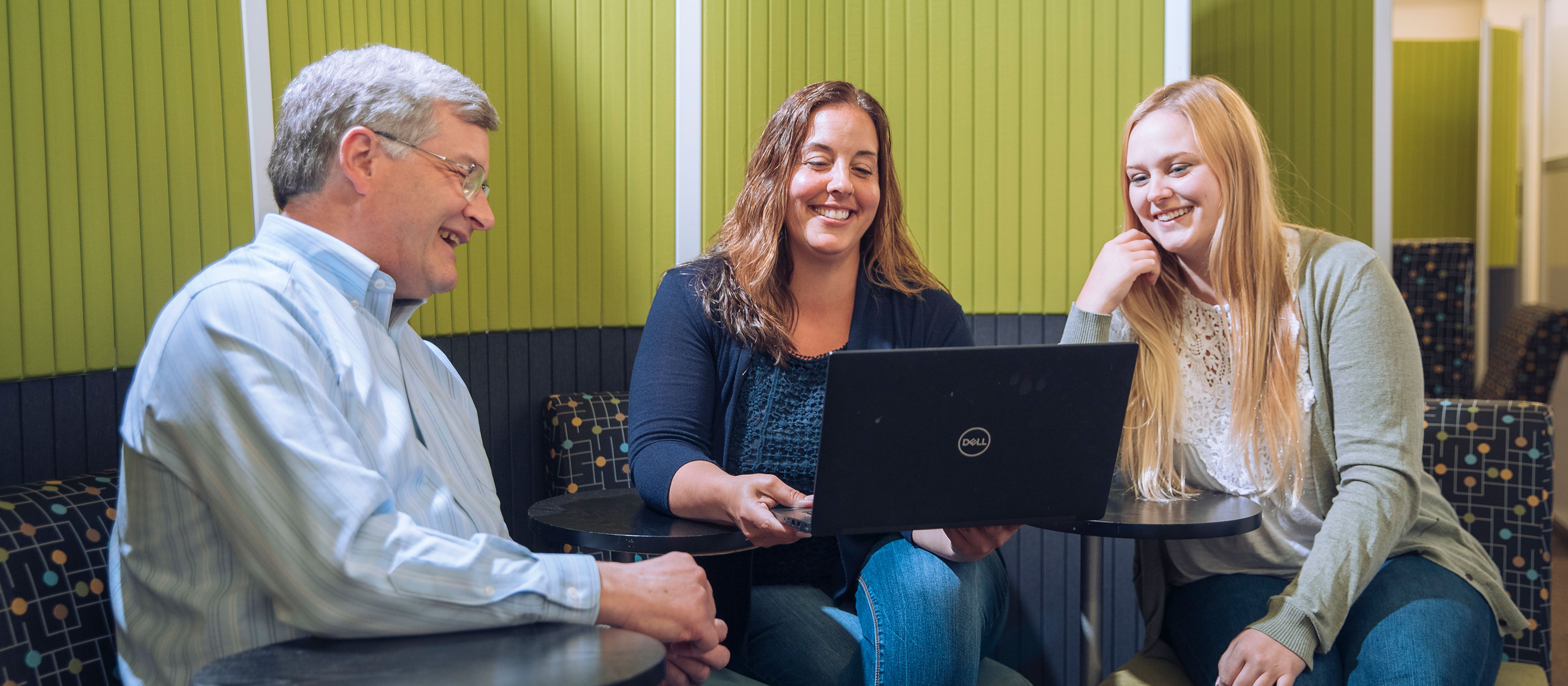 Man and two women looking at a laptop 