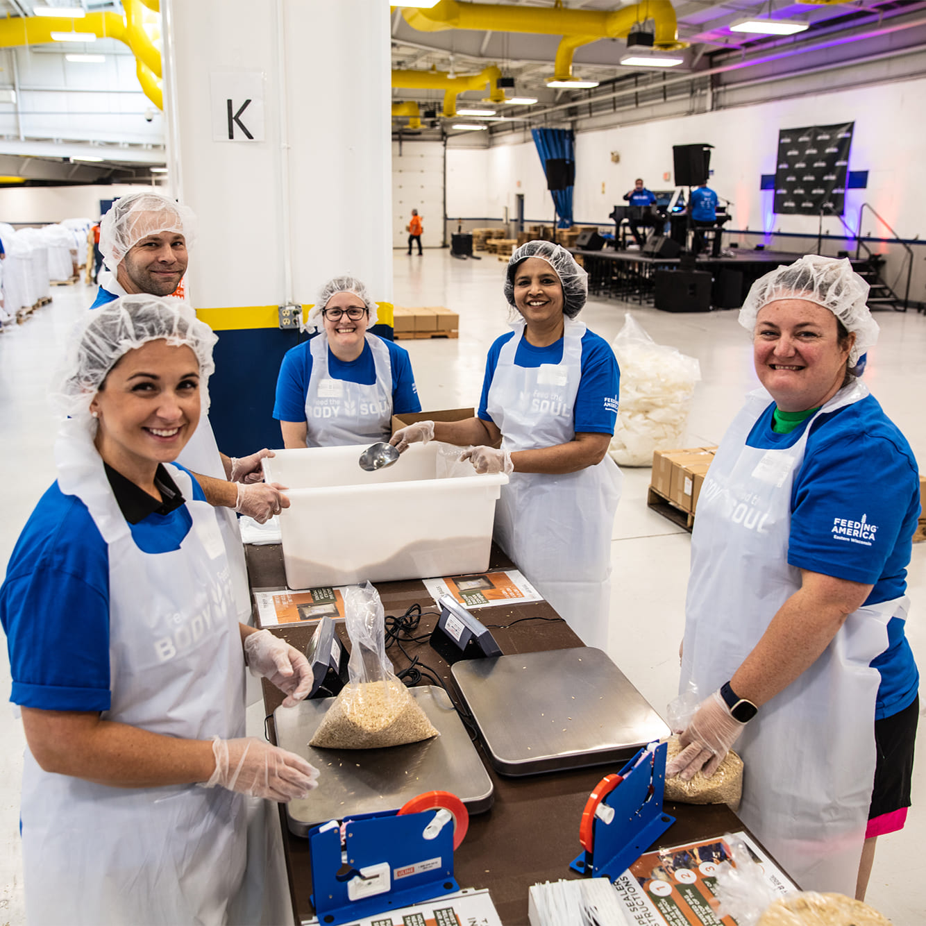 Team members at a rice packing table wearing hair nets and aprons