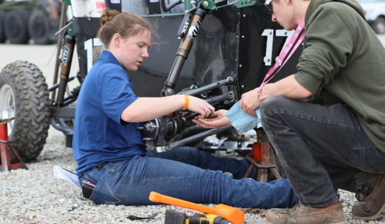 Students from the Baja SAE Oshkosh event making final adjustments to their vehicle
