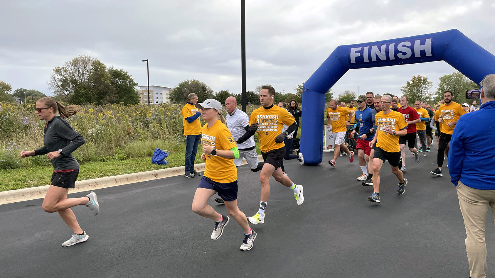 Oshkosh team members and community members crossing the finish line for a United Way outdoor run